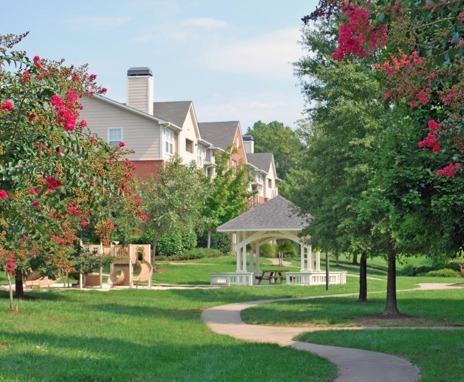a large green lawn with trees and a gazebo and walkway