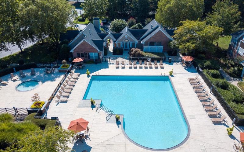 a swimming pool in a courtyard with lounge chairs and a clubhouse