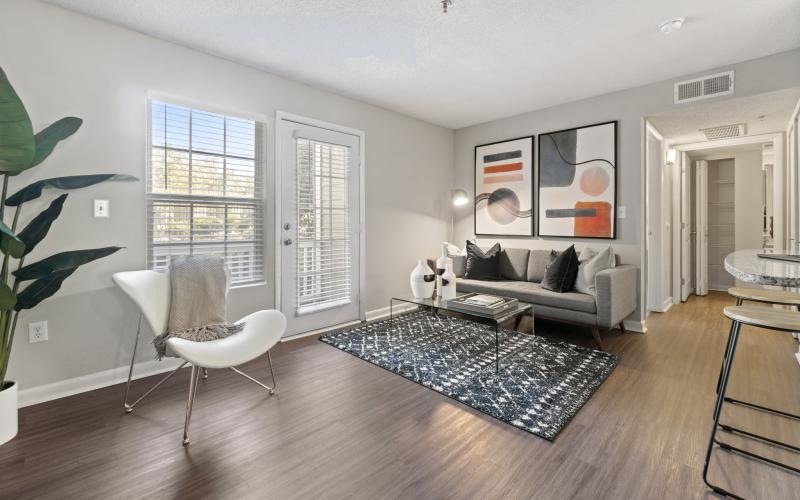 a living room with a couch and chairs and windows
