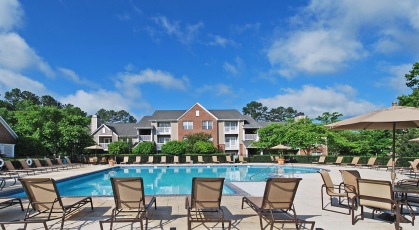 Resort-style swimming pool plaza with lounge seating and umbrellas