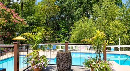 Balcony overlooking pool area with shaded seating and tables