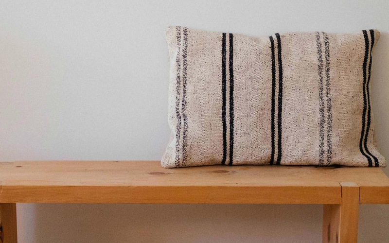 a wooden bench with a striped pillow on it