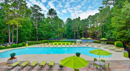 Spacious pool area surrounded by shaded tables and lounge chairs