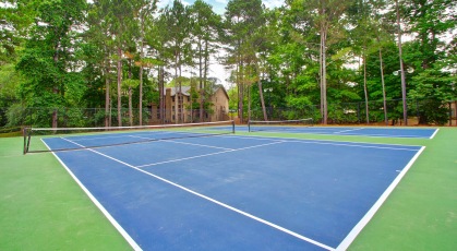 Gated tennis courts surrounded by mature trees