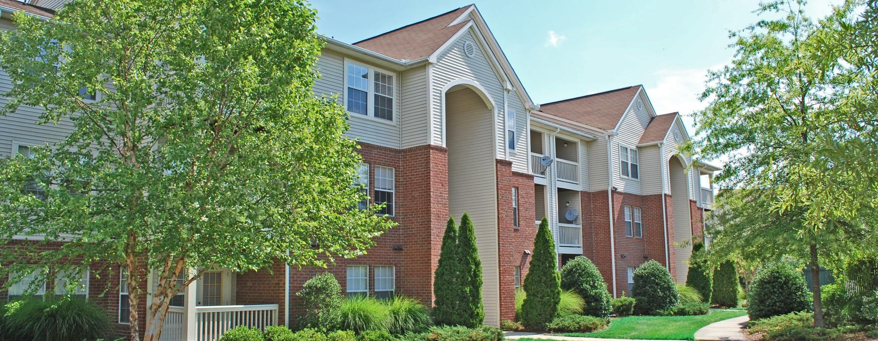 a large brick building with trees in front of it and a lawn