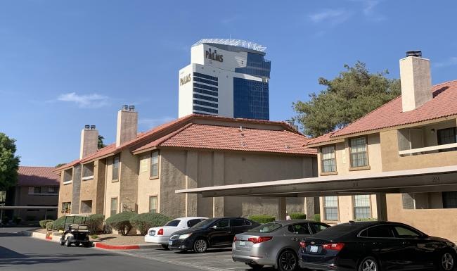 a building with parking lot and a tower in the background