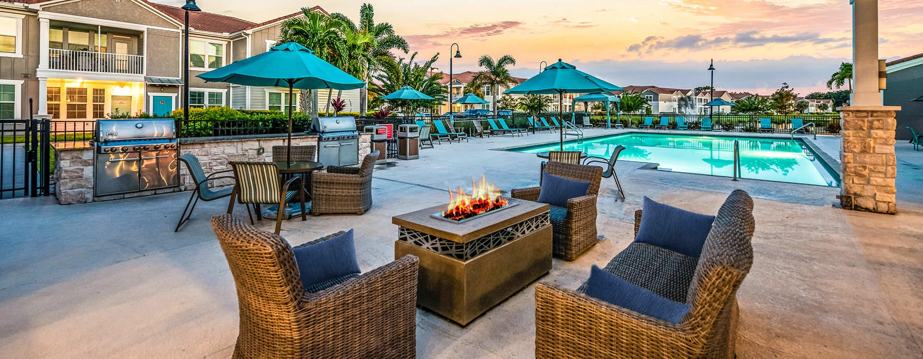 wicker chairs around outdoor fire pit near pool