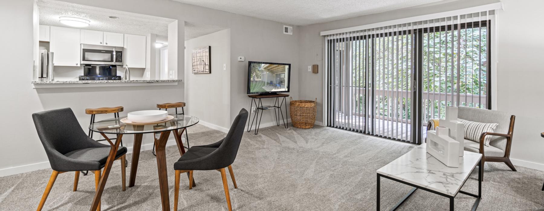 a living room with a table and chairs and a glass balcony door