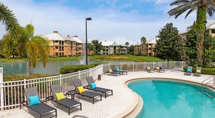 Swimming pool with lounge seating and umbrellas next to lake