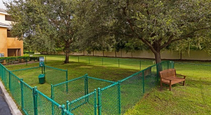 Fenced in bark park shaded by mature trees with bench seating