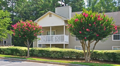 Apartment exterior building with balcony overlooking parking lot and well manicured landscaping