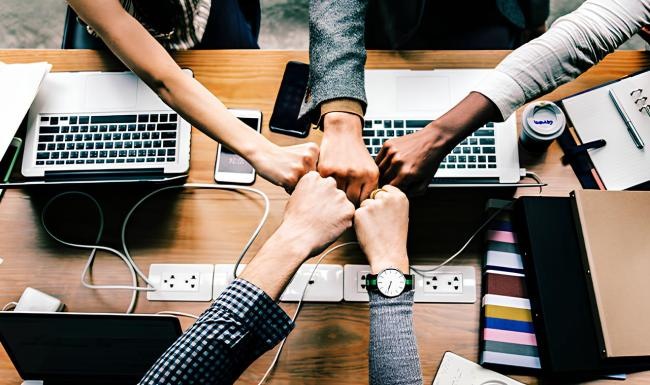 a group of people fist bumping with computers