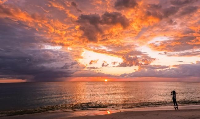 a person standing on a beach at sunset