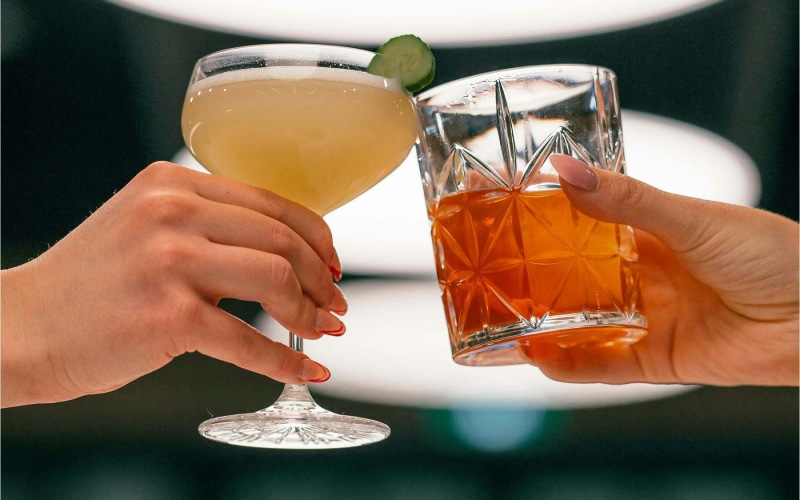 hands holding glasses with cocktails