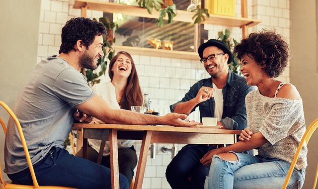 group of friends laughing around a restaurant table