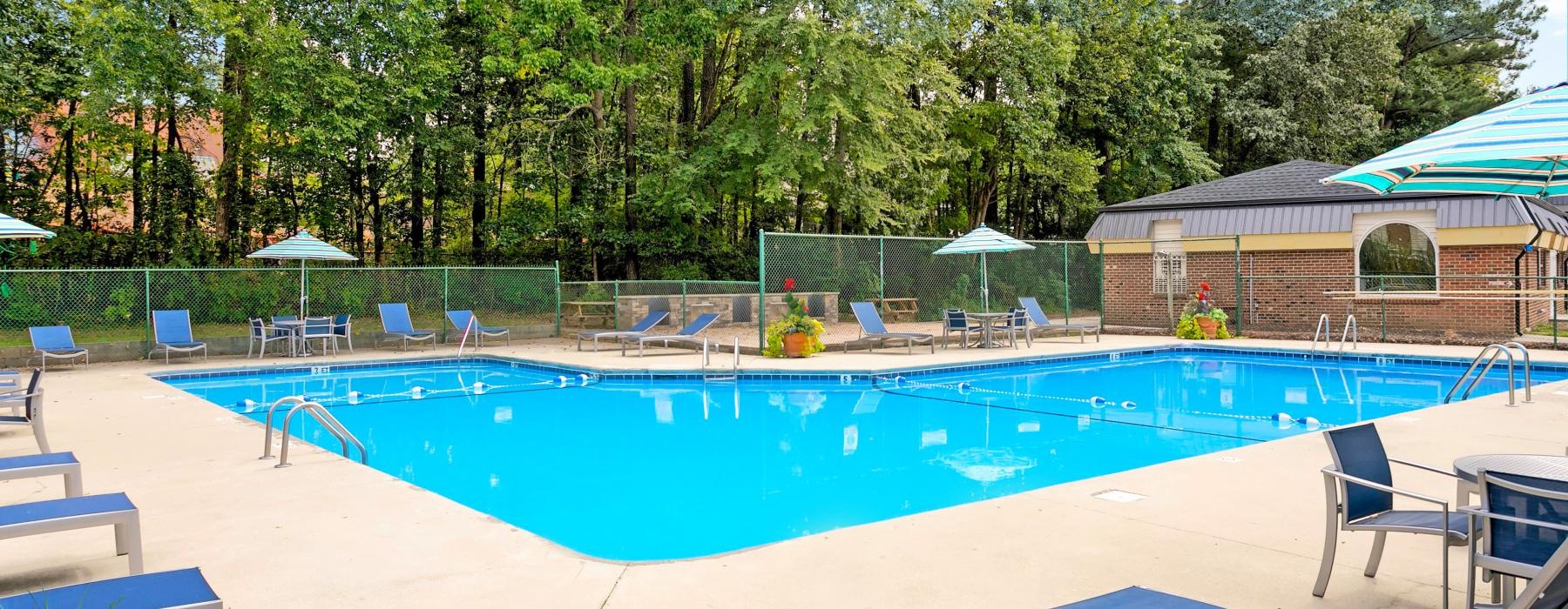 a swimming pool with a fence and trees in the background