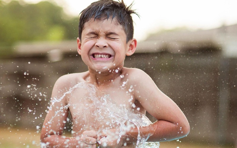 water splashing on a boy in the yard