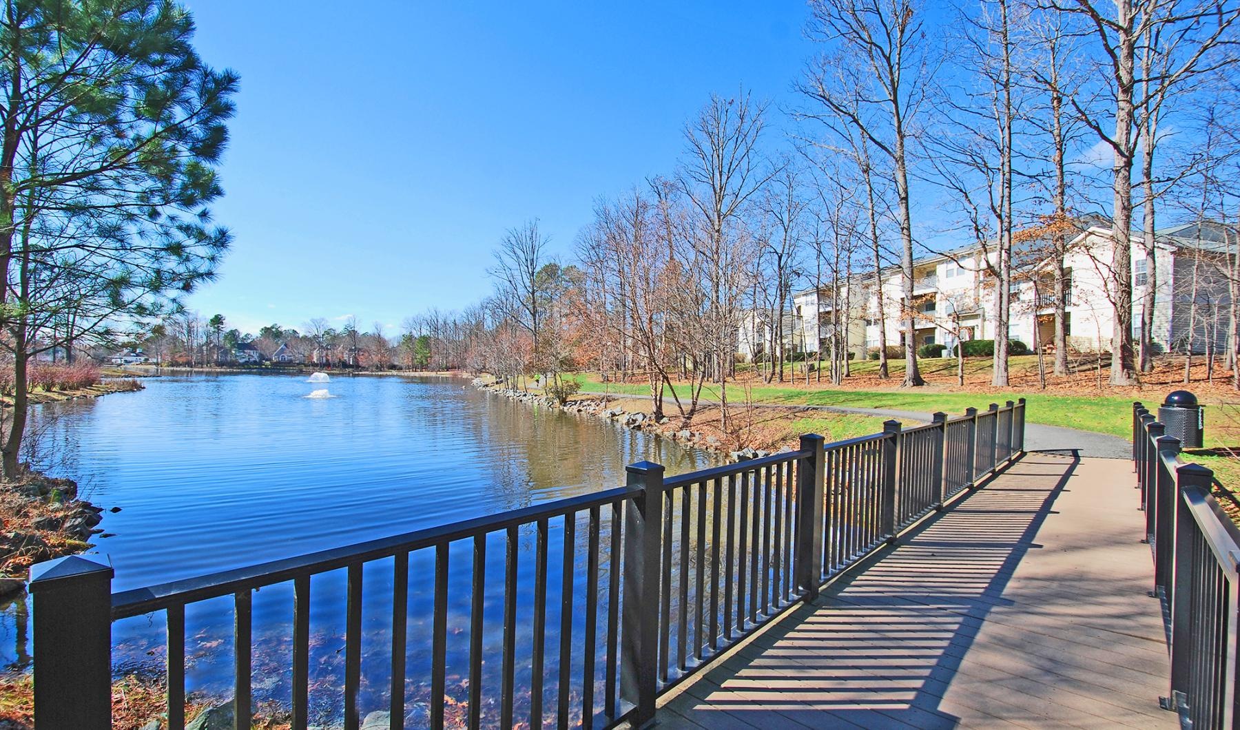 a wooden bridge over a body of water with trees and buildings in the background