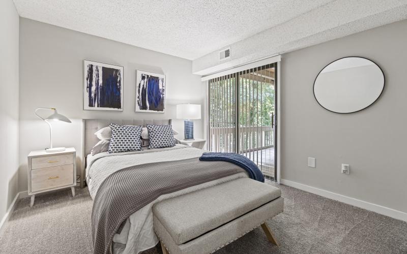 a bedroom with a bed and a mirror and balcony access