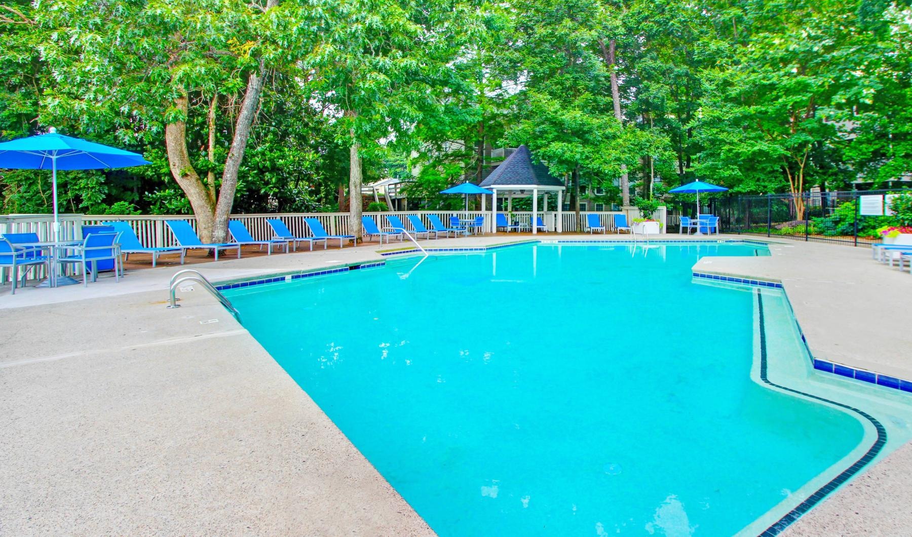 a swimming pool with blue chairs and umbrellas