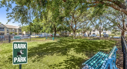 Fenced in bark park shaded by mature trees with bench seating