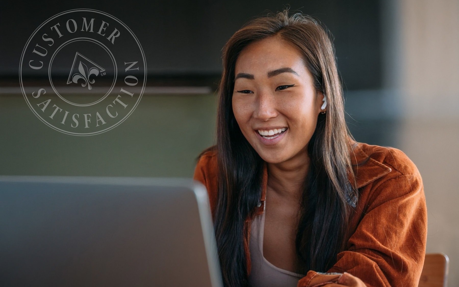 a woman smiles while she looks at a computer screen