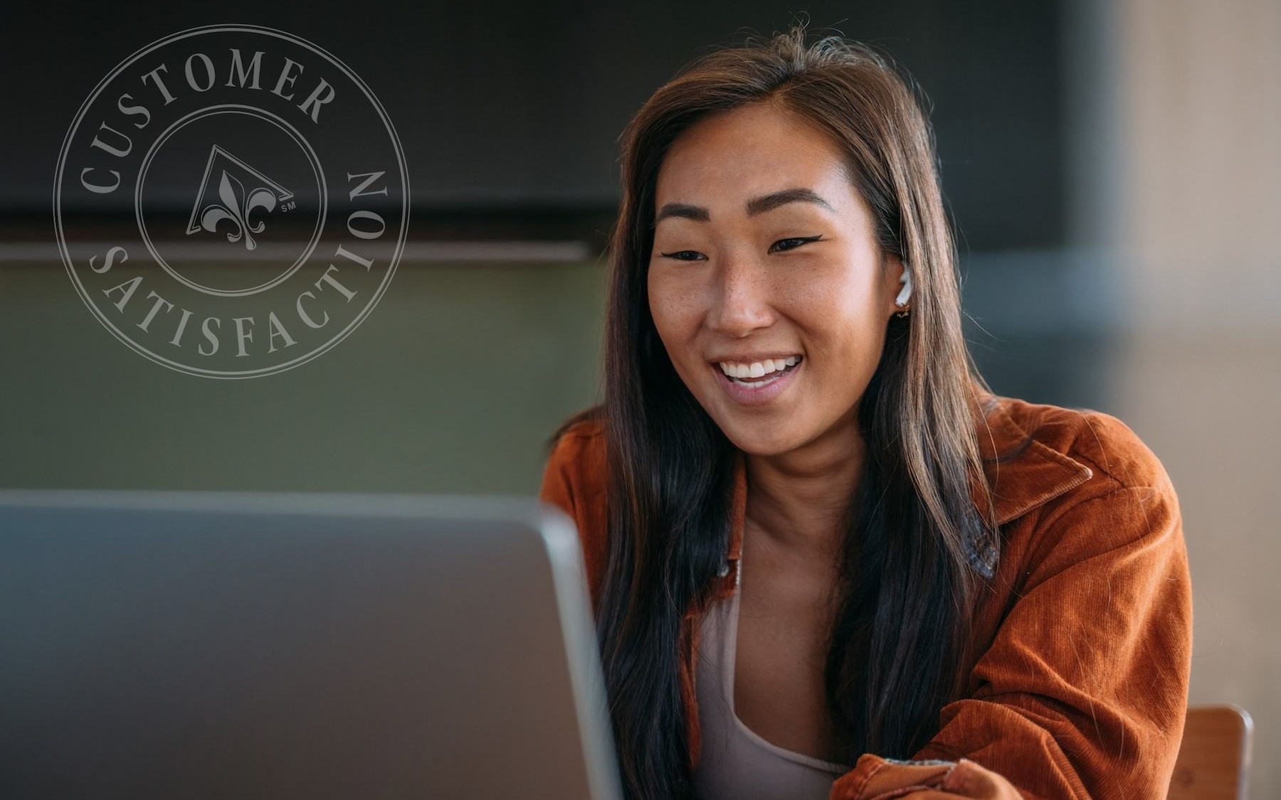 a woman smiles while she looks at a computer screen