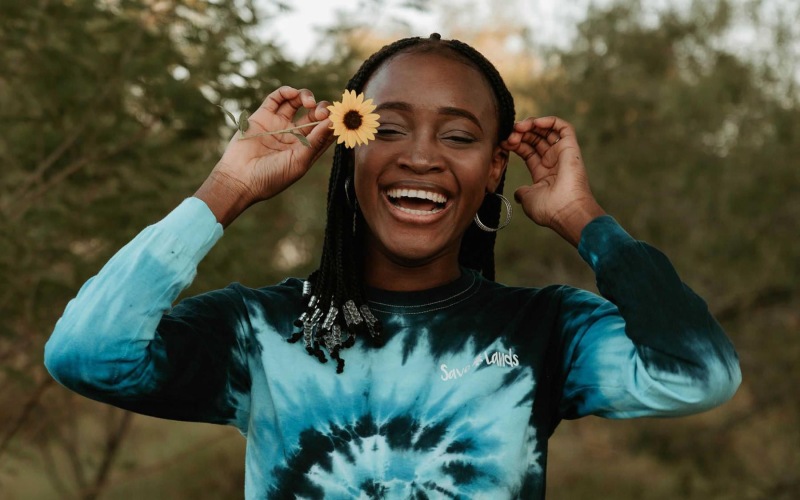 woman holds a flower in her hair in a park