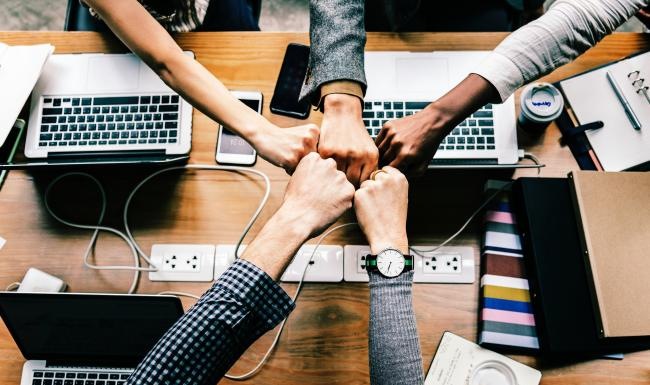 a group of people fist bumping over a table