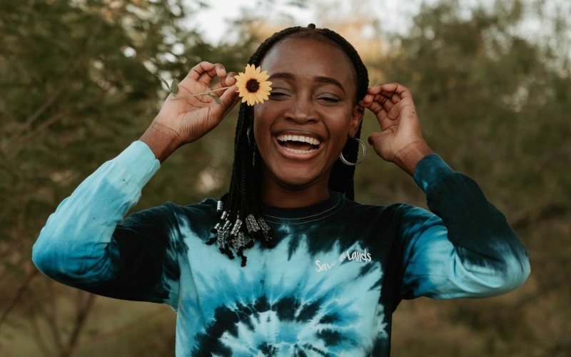 woman holds a flower in her hair in a park