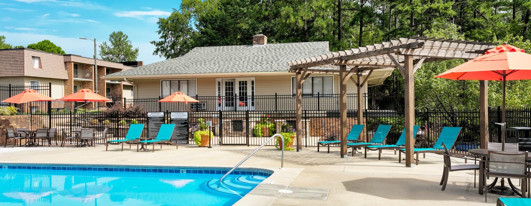 a pool with chairs and umbrellas by a building