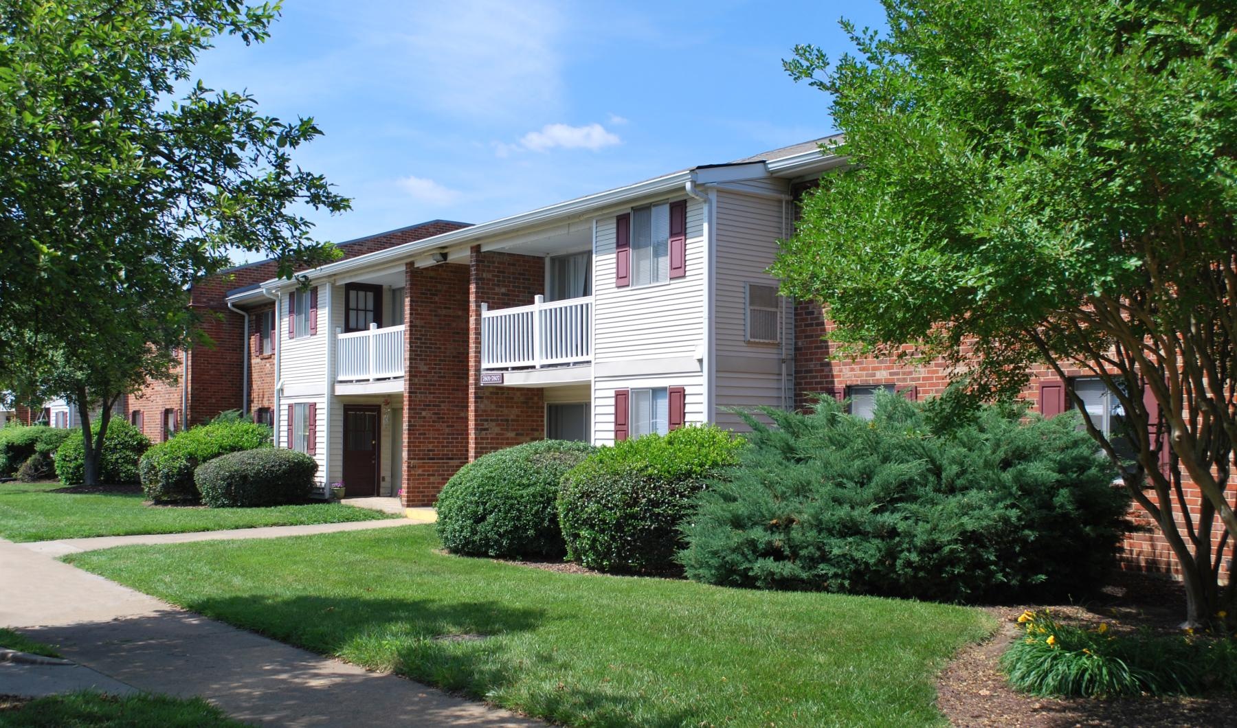 a brick house with a lawn and trees in front of it