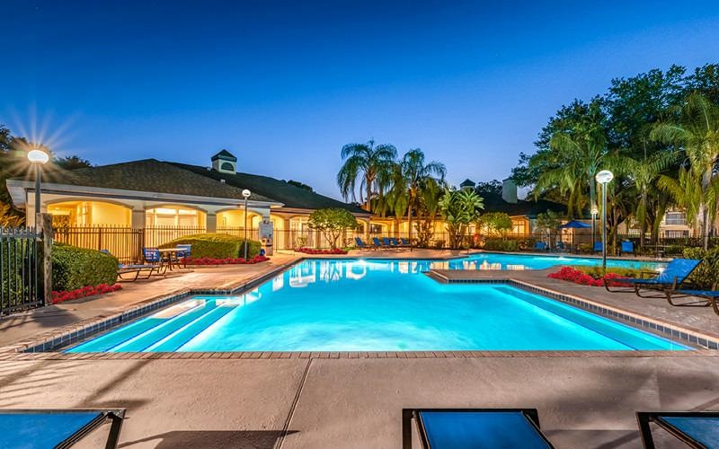 a swimming pool with trees and a building in the background
